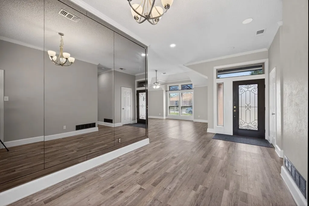 Foyer entrance featuring a chandelier, ornamental molding, dark wood-style flooring, and ceiling fan