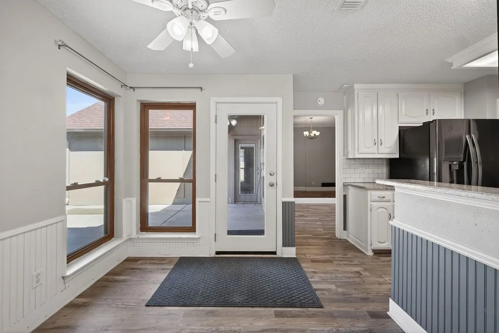 Kitchen featuring light countertops, white cabinetry, black refrigerator with ice dispenser, a ceiling fan, and a textured ceiling