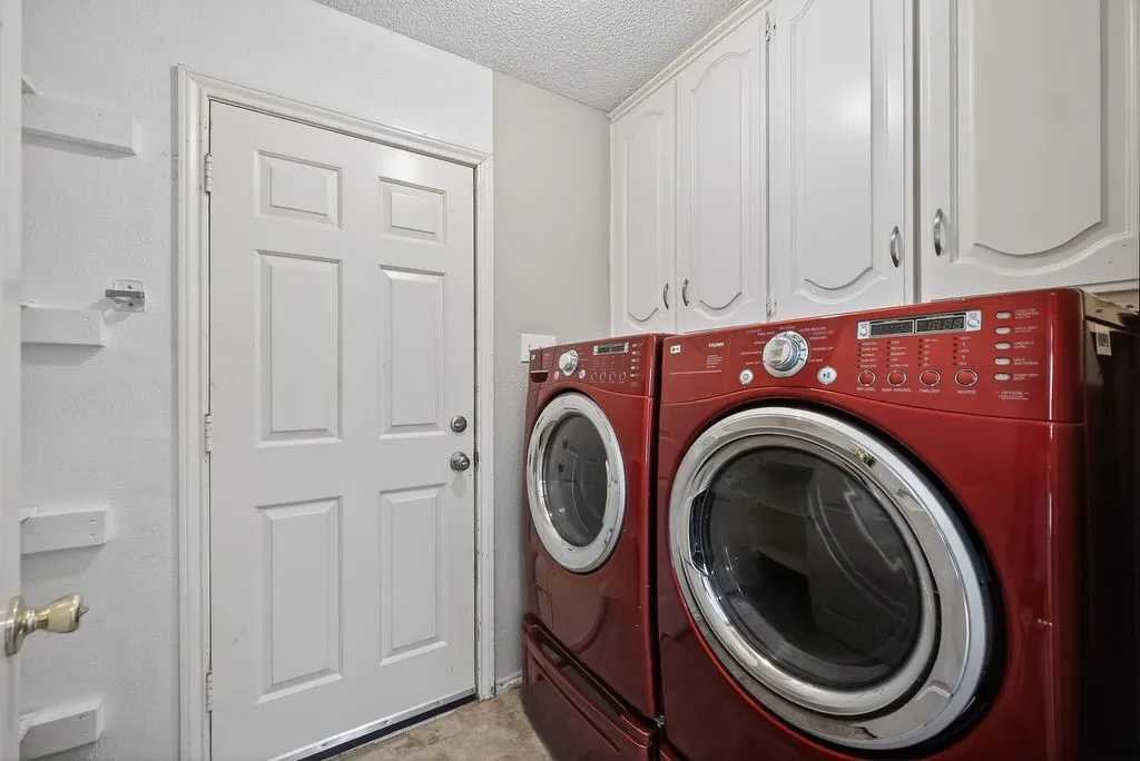 Laundry room featuring washing machine and dryer, a textured ceiling, and cabinet space