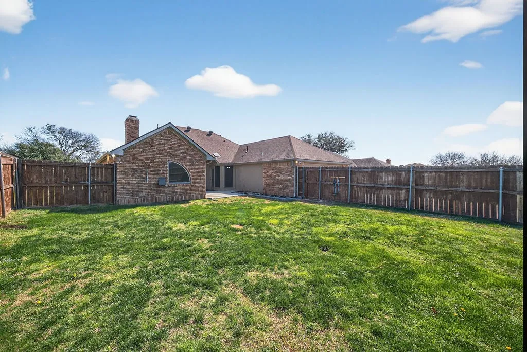 Back of property with a chimney, a patio area, brick siding, and a fenced backyard
