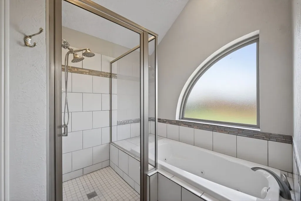 Bathroom featuring a jetted tub and a stall shower