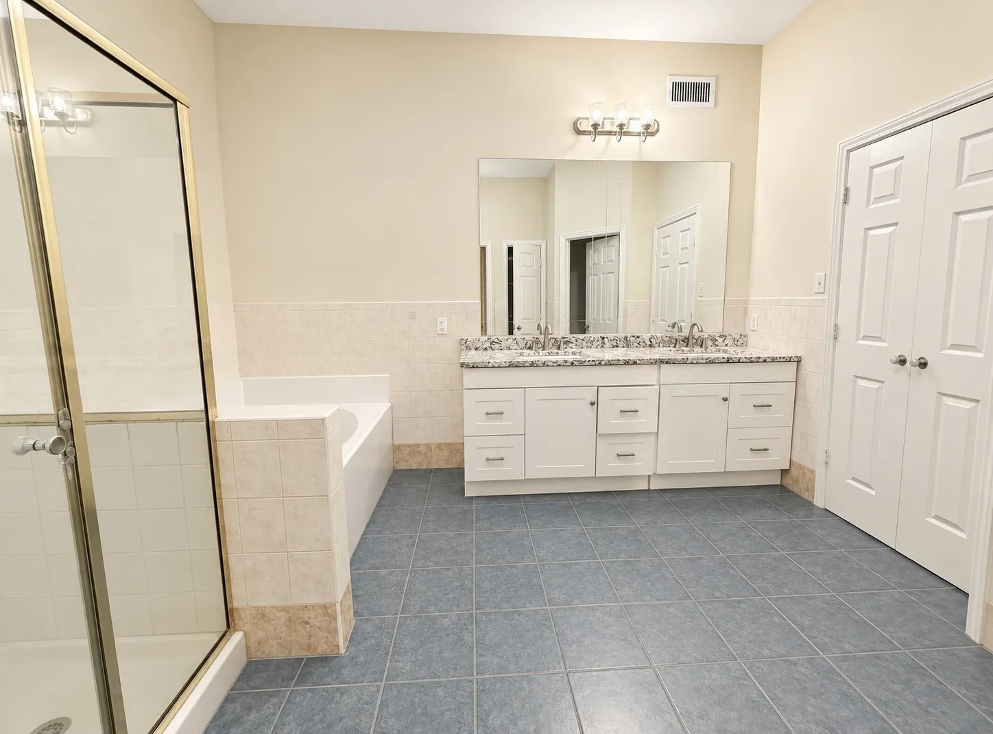 Dual vanity with granite-style countertop, white cabinetry, and undermount sinks