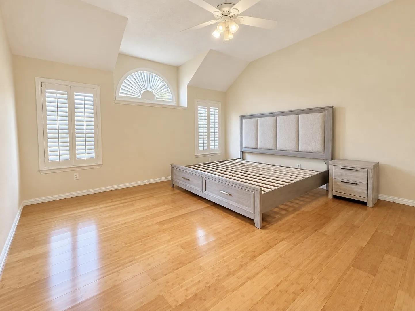 Vaulted ceiling, ceiling fan, arched window, wood-finish flooring, plantation shutters