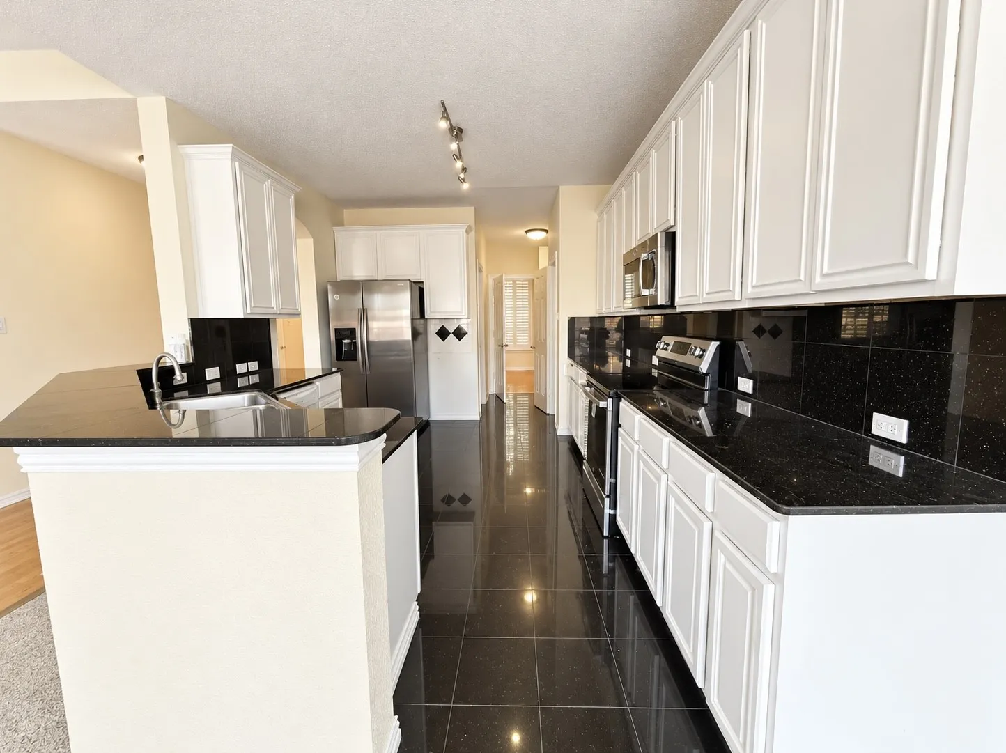 Kitchen featuring dark tile flooring, white cabinetry, dark countertops, and stainless steel appliances