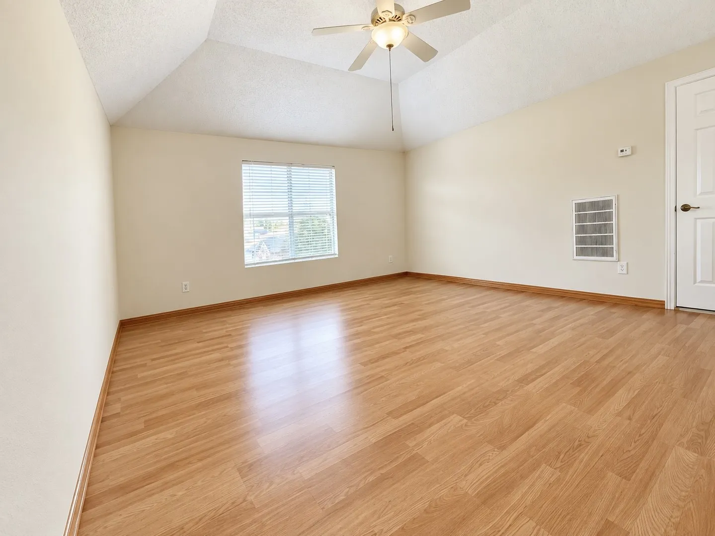 Vaulted ceiling, wood-finish flooring, ceiling fan with integrated lighting, window with blinds, panel door