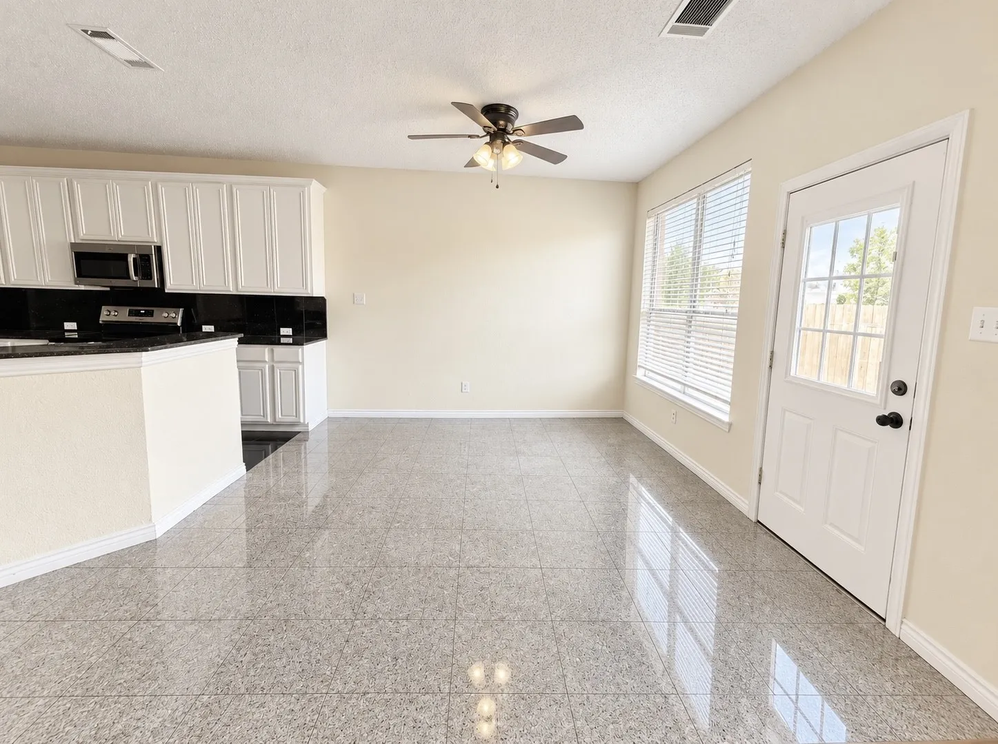 Open-concept living area featuring glossy tile flooring, a ceiling fan, and white cabinetry