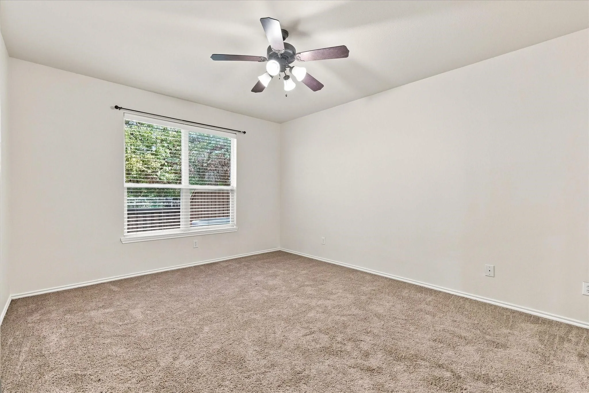 Neutral tone wall paint, carpeted flooring, window with blinds, and a ceiling fan with integrated lighting