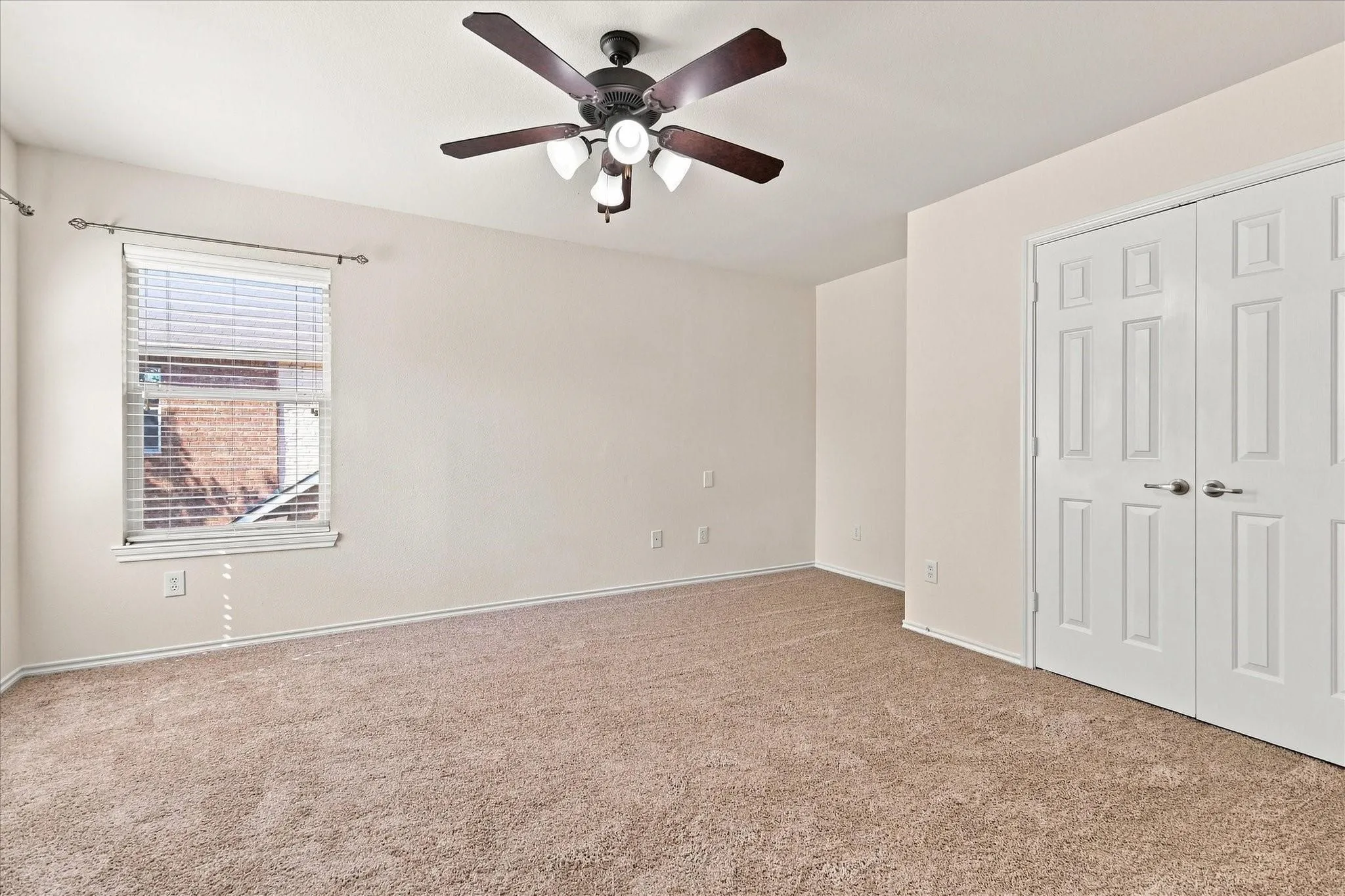Recessed window with blinds, ceiling fan with integrated lighting, textured carpet, and double bi-fold doors