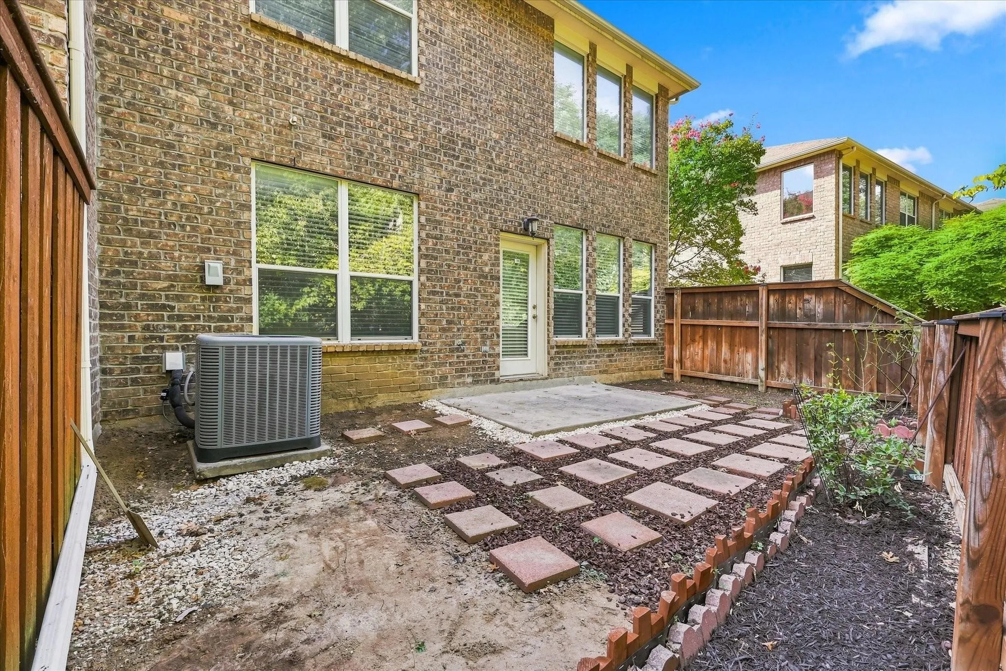 Brick exterior with multiple windows, a rear patio, and a stone paver pathway