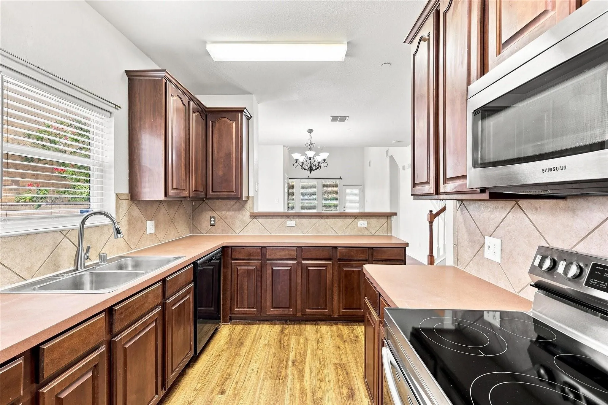 Well-appointed kitchen featuring wood-finish cabinetry, a stainless steel sink, tile backsplash, and integrated stainless steel appliances