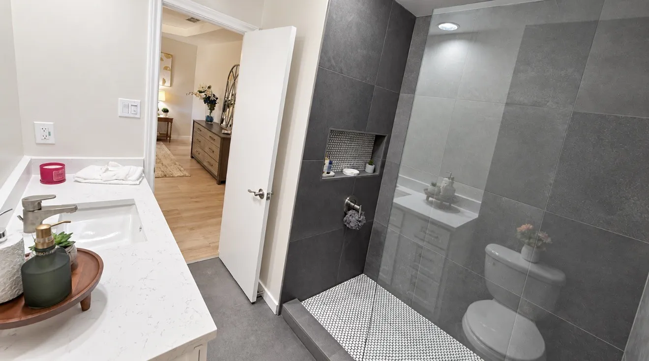 Shower with full-height tile surround, built-in recessed shelf, and glass panel enclosure