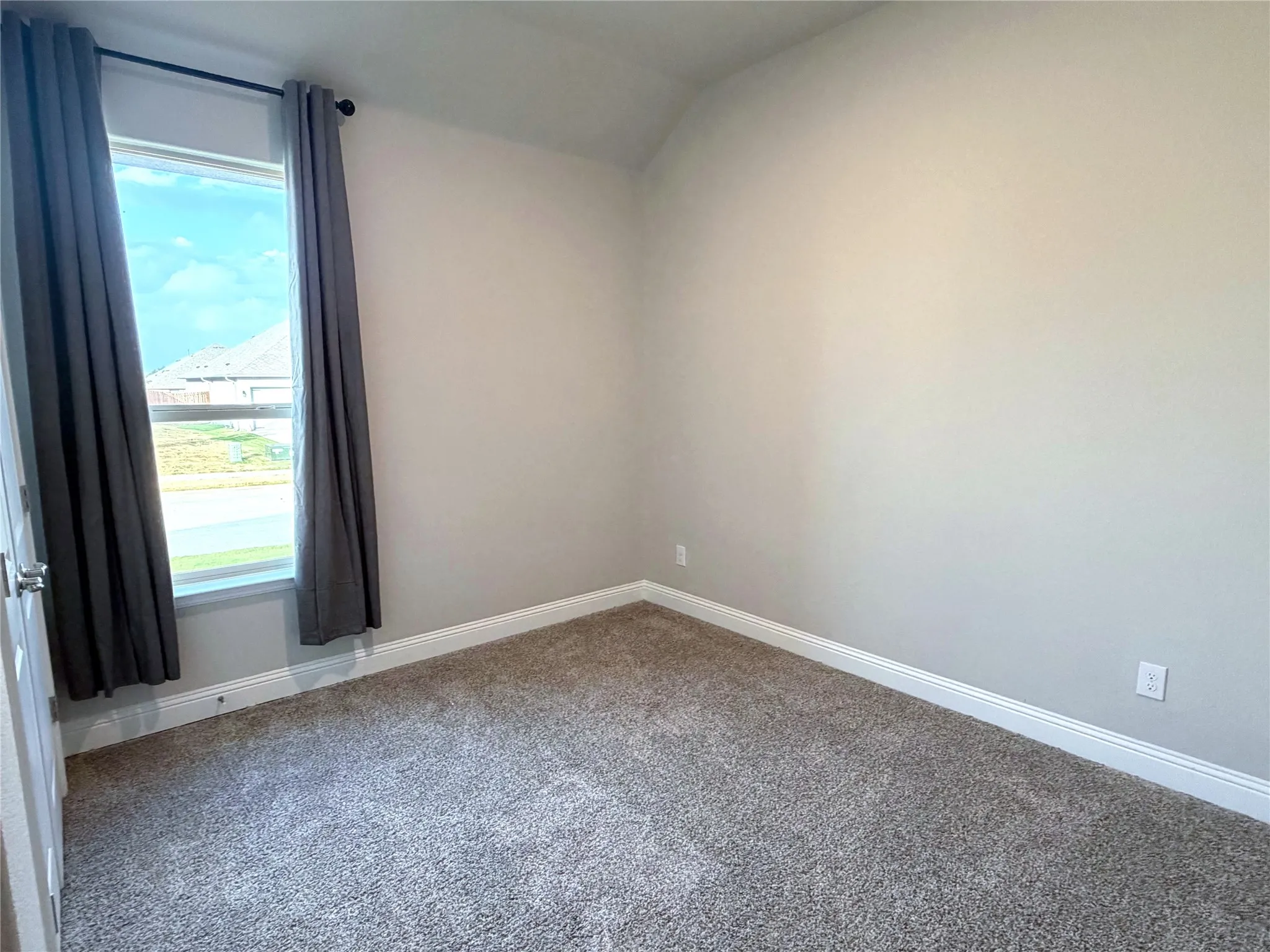 Plush carpet flooring, neutral wall tones, and a window with white trim
