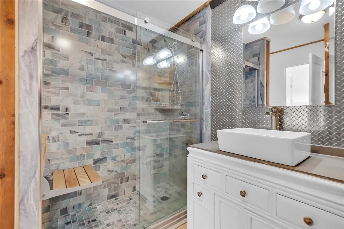 Primary bathroom with large walk in shower, teak bench and vessel sink