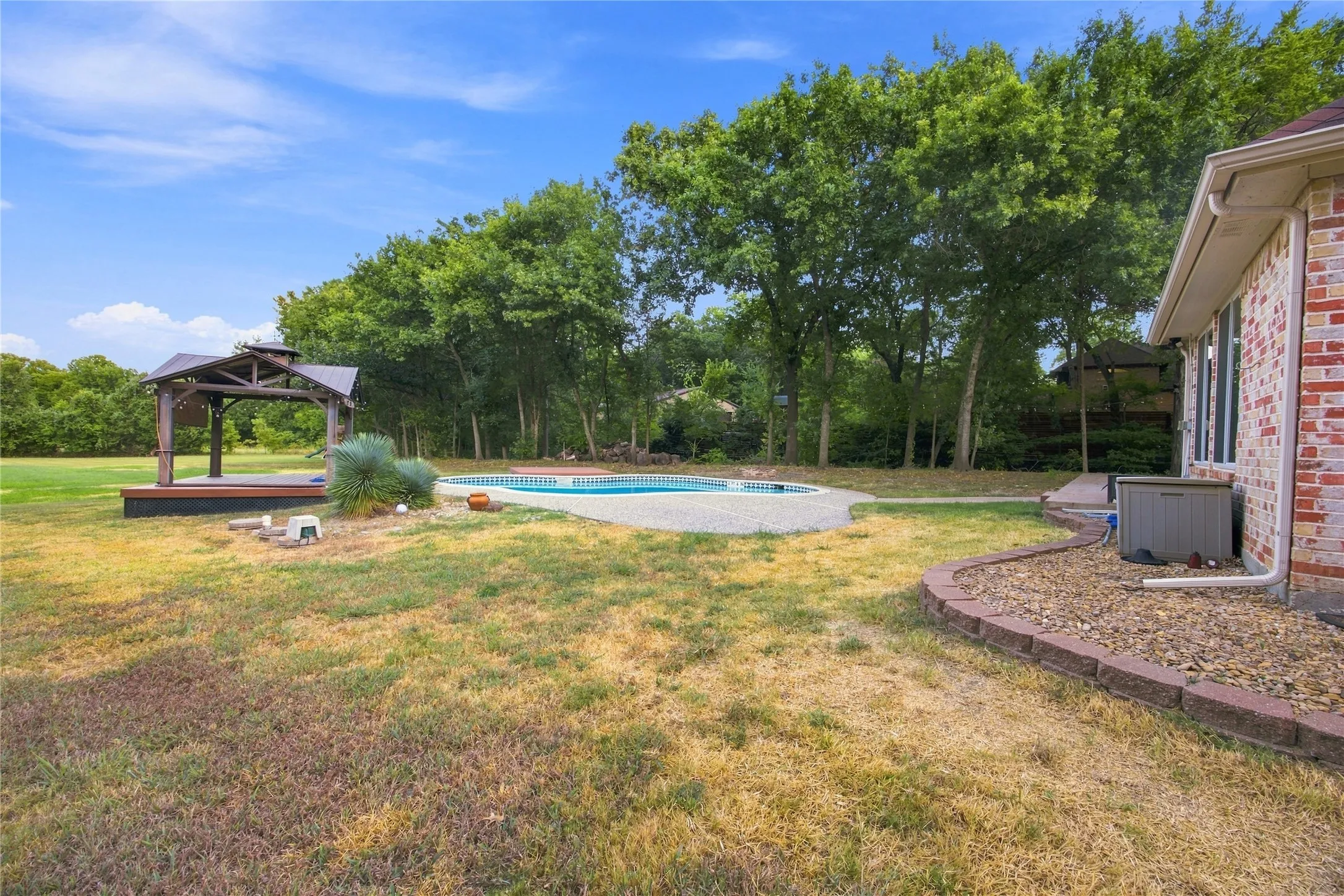 Backyard featuring an in-ground swimming pool, a wooden gazebo with a raised deck, and mature trees