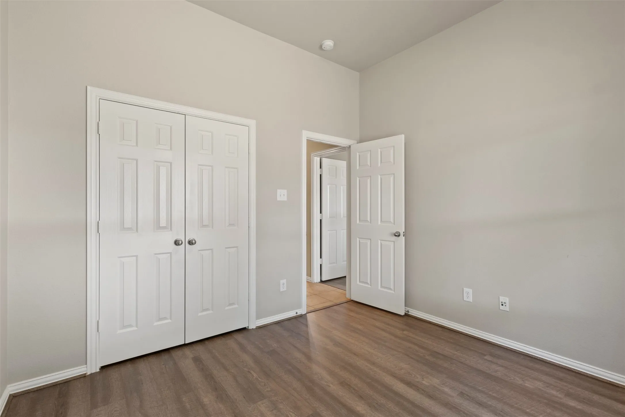 Vaulted ceiling, wood-finish flooring, light gray wall color, white trim, white paneled doors