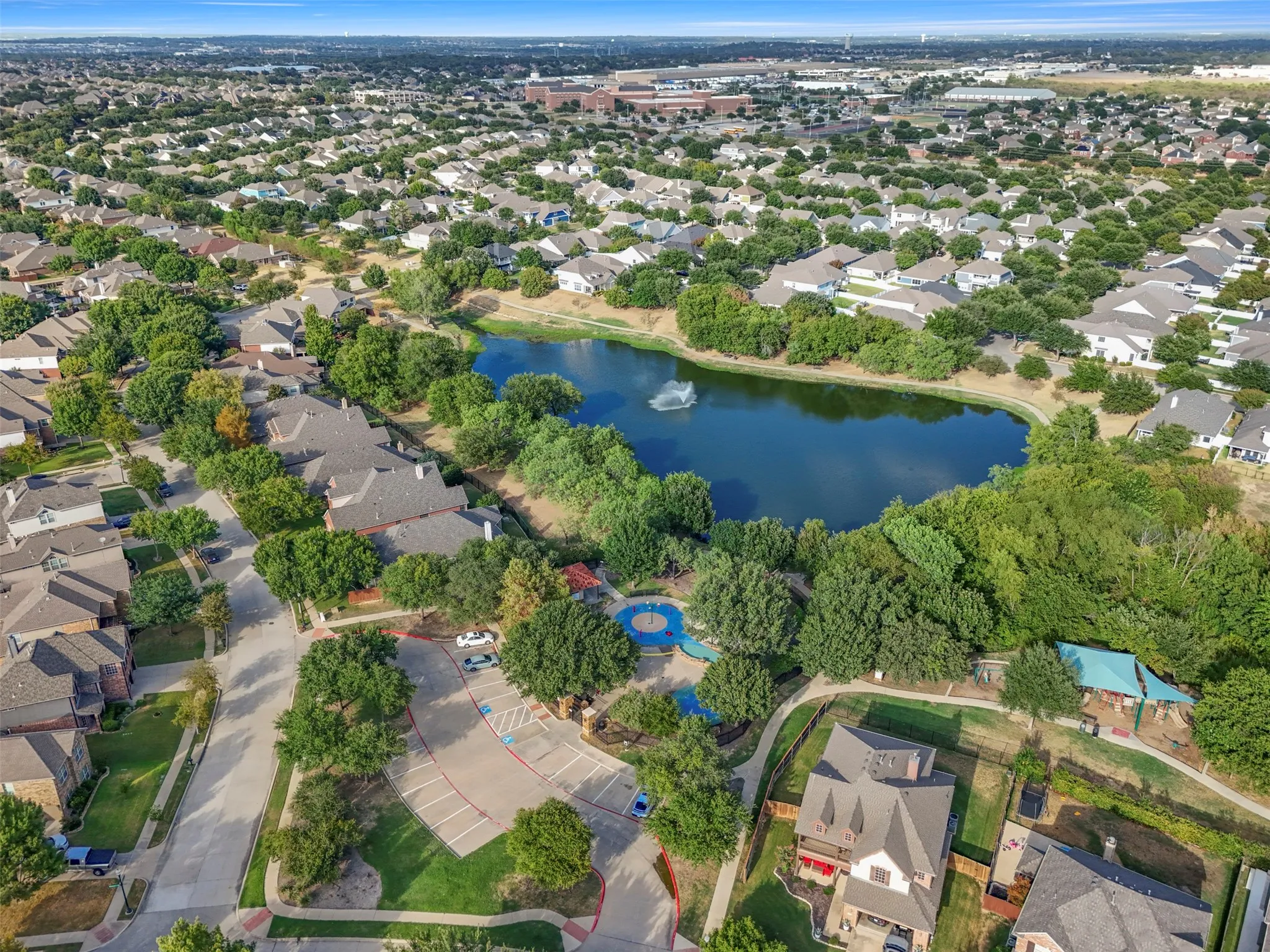 Neighborhood featuring a central pond with a fountain, a community park, and mature trees