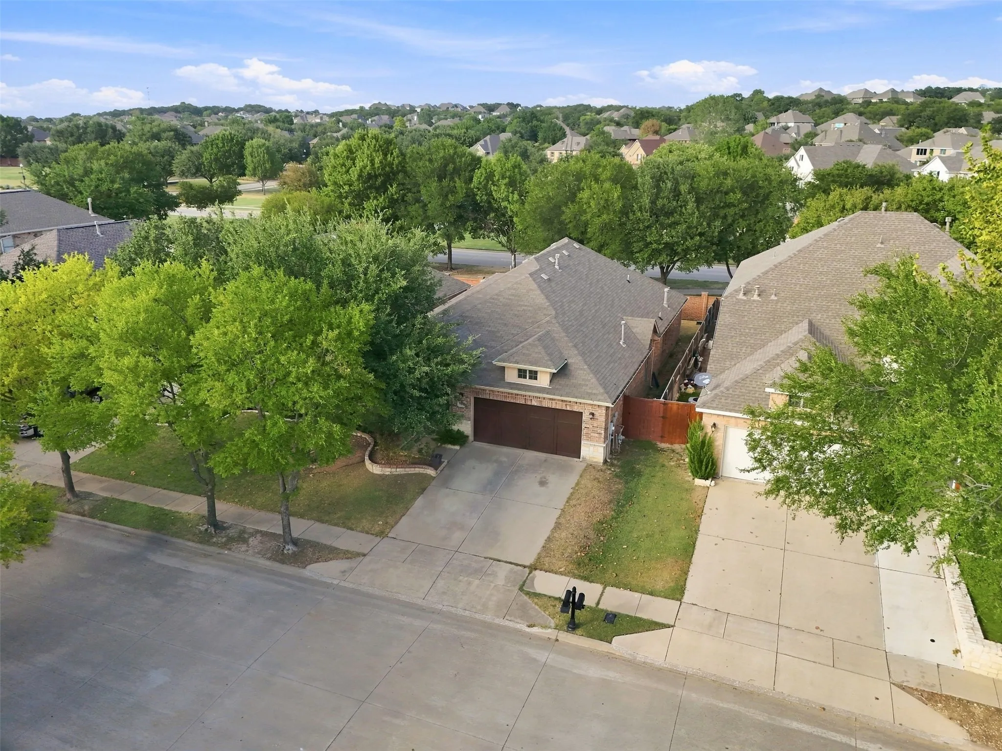 Brick-clad exterior with an attached garage, concrete driveway, and front lawn landscaping