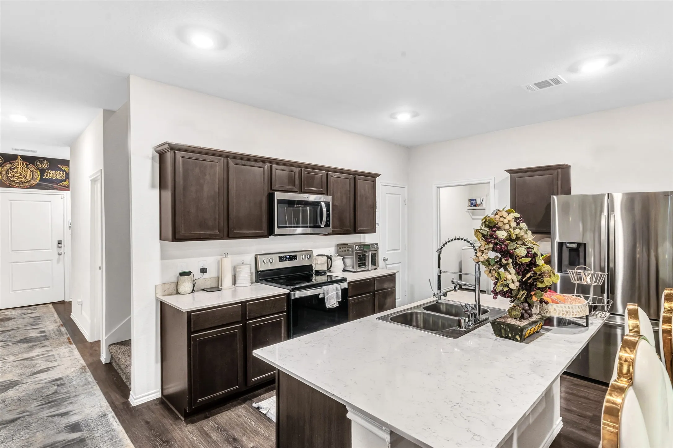 Kitchen featuring dark brown cabinetry, sink, a center island with sink, stainless steel appliances, and dark hardwood / wood-style flooring