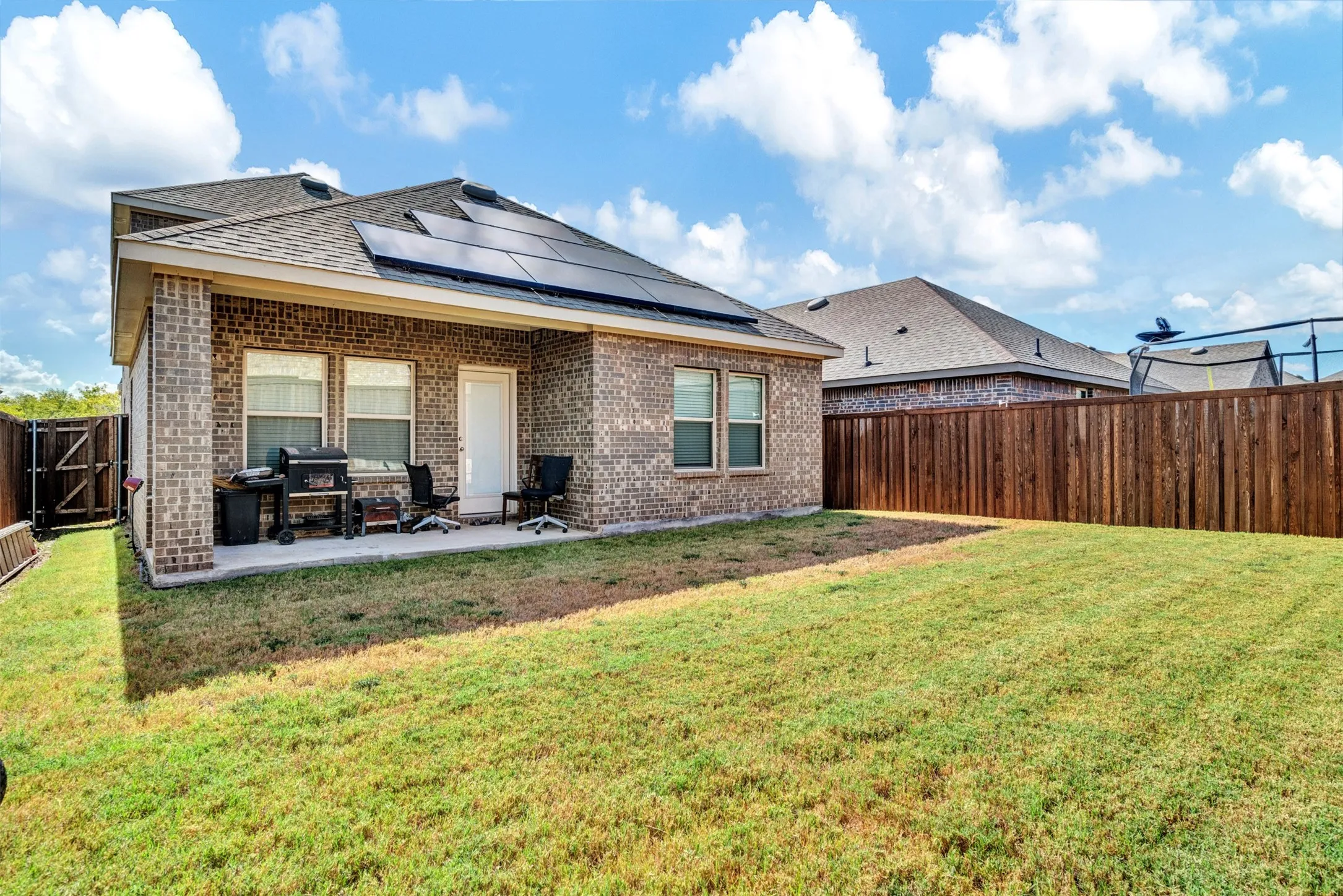 Back of property featuring solar panels, a yard, and a patio