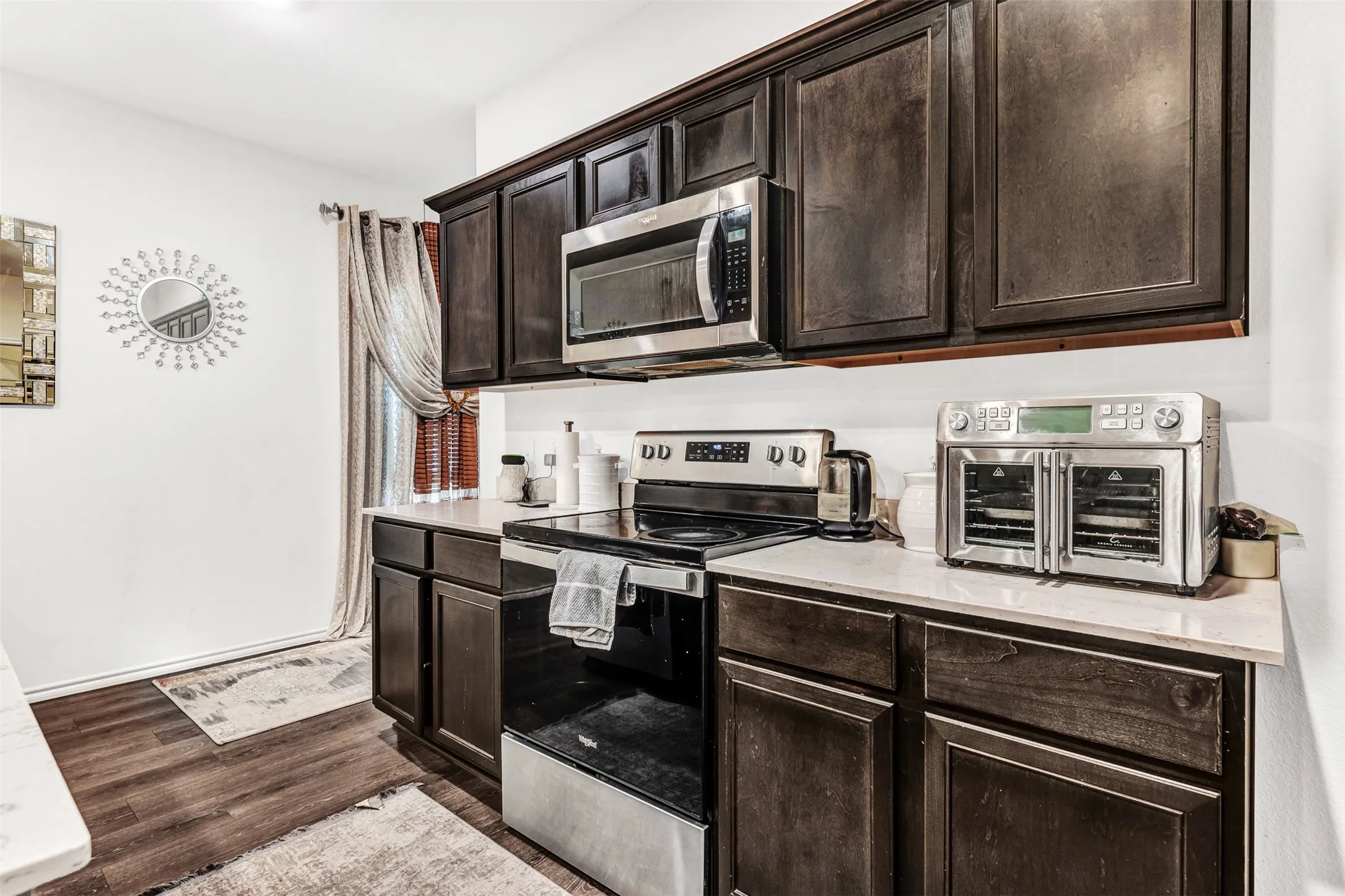 Kitchen featuring dark brown cabinets, stainless steel appliances, and dark hardwood / wood-style floors