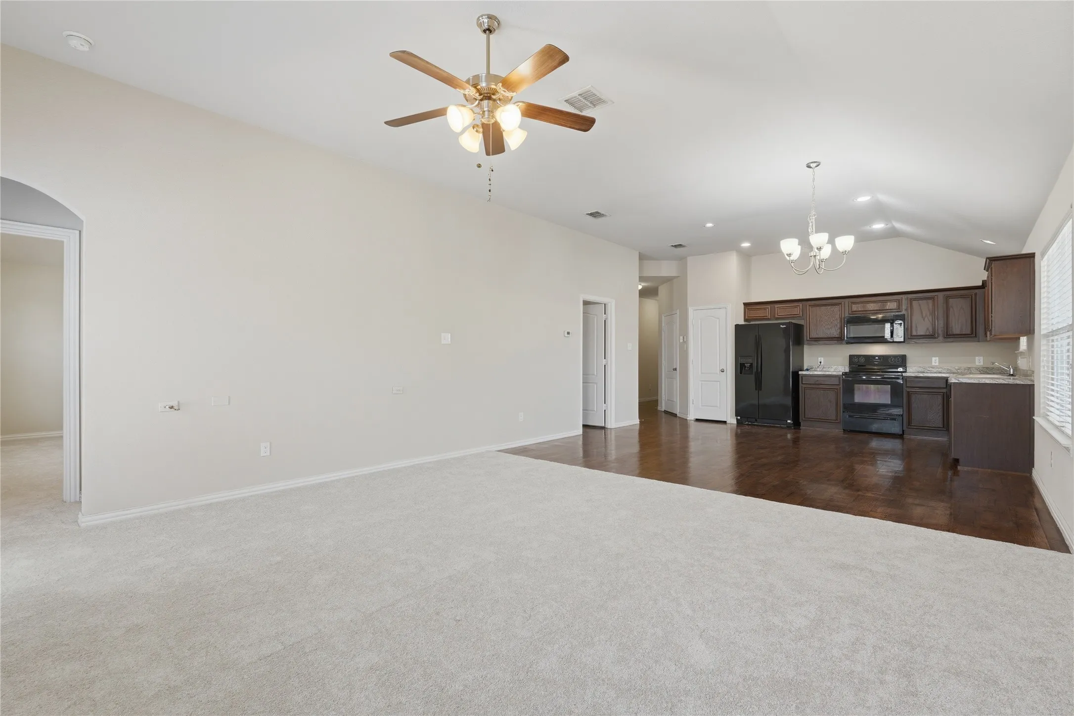 Vaulted ceiling, ceiling fan, carpet flooring, wood-finish flooring, dark wood cabinetry
