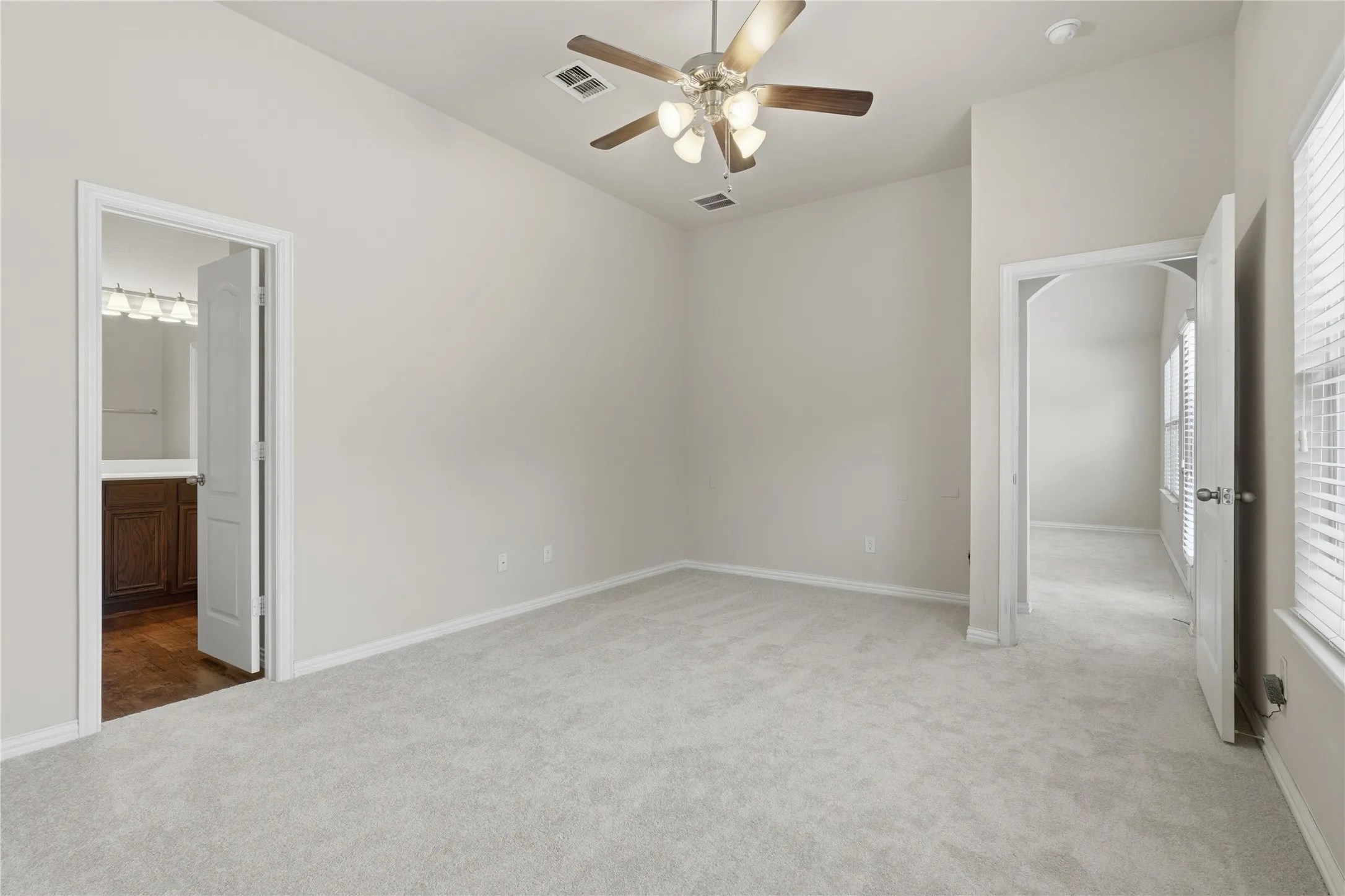 Vaulted ceiling with a ceiling fan light fixture, light gray carpeting, and white walls