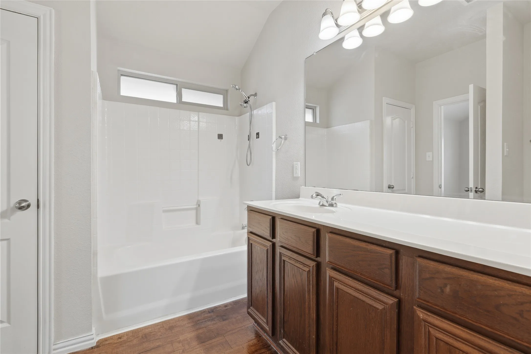 Bathroom featuring a spacious vanity with white countertop, integrated sink, and wood-finish cabinetry