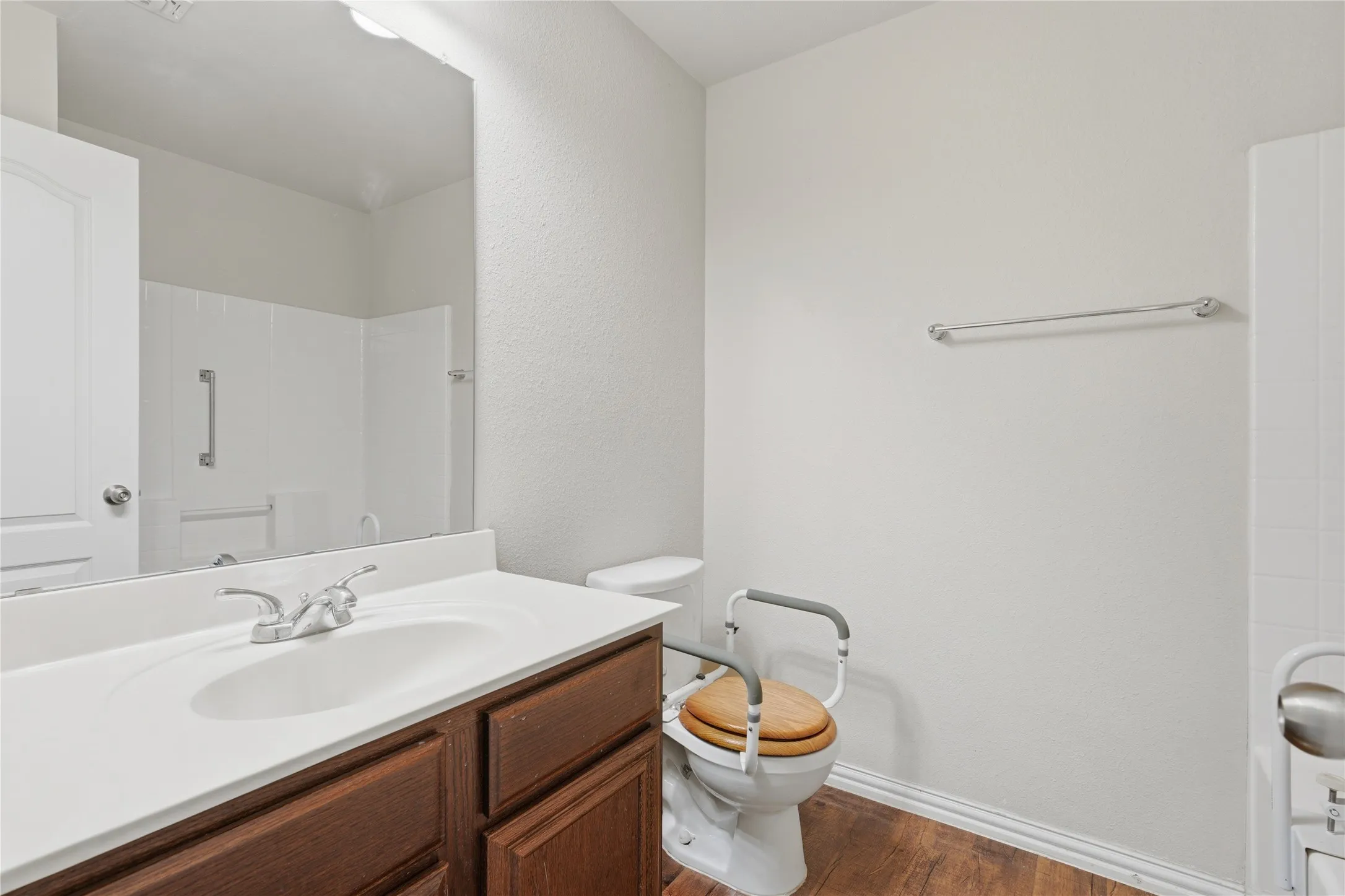 Bathroom featuring a vanity with a white countertop, wood-finish cabinetry, a white porcelain sink, and a chrome faucet