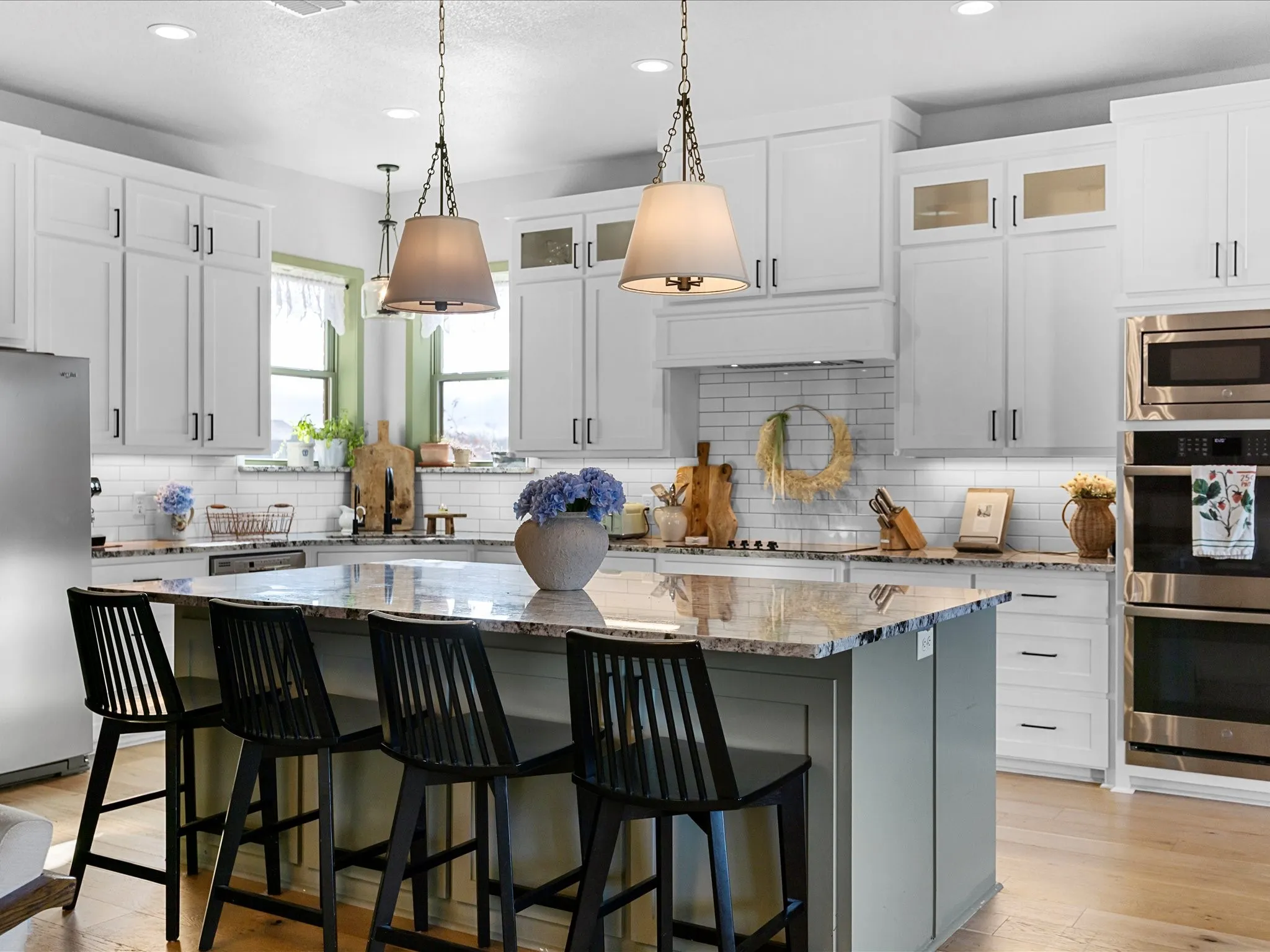Kitchen with a center island featuring a granite countertop, white shaker-style cabinetry, and stainless steel built-in appliances