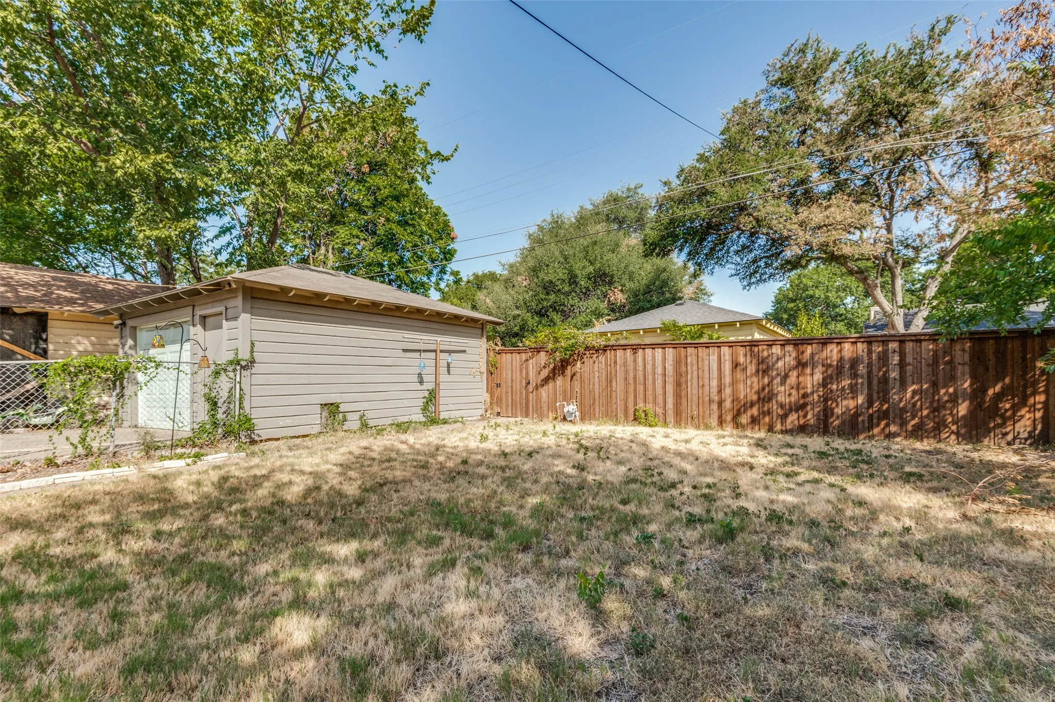 Expansive rear yard with a wood fence and mature trees