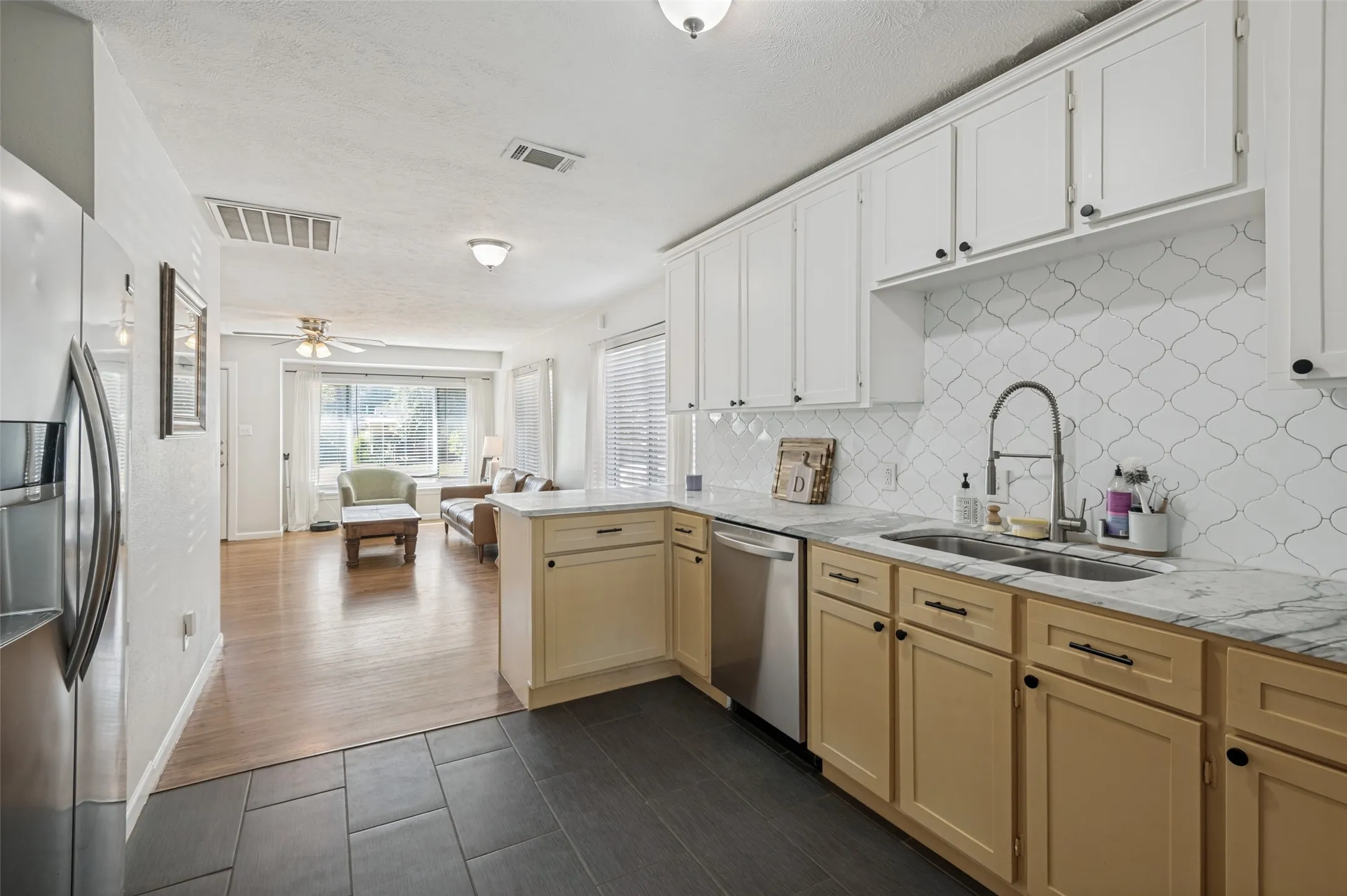 Kitchen featuring two-tone cabinetry, patterned tile backsplash, and stainless steel appliances