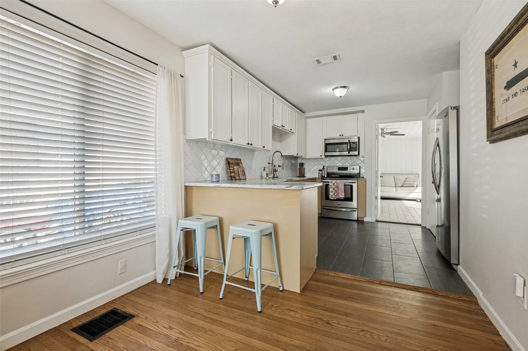 Kitchen with white cabinetry, stainless steel appliances, a tile backsplash, and a breakfast bar