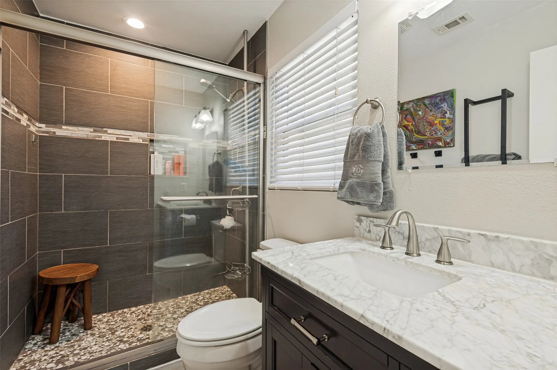 Walk-in shower with dark tile surround and glass enclosure