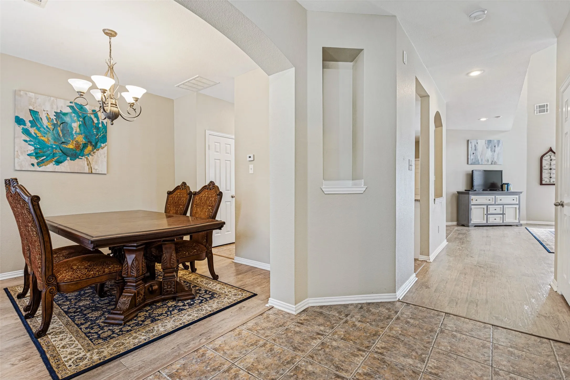 Recessed wall niche, arched doorways, tiled flooring, wood-finish flooring, and a decorative chandelier