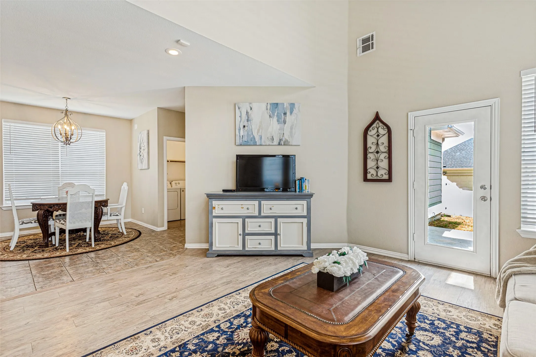 Vaulted ceilings with recessed lighting, wood-finish flooring, and a glass-paneled exterior door