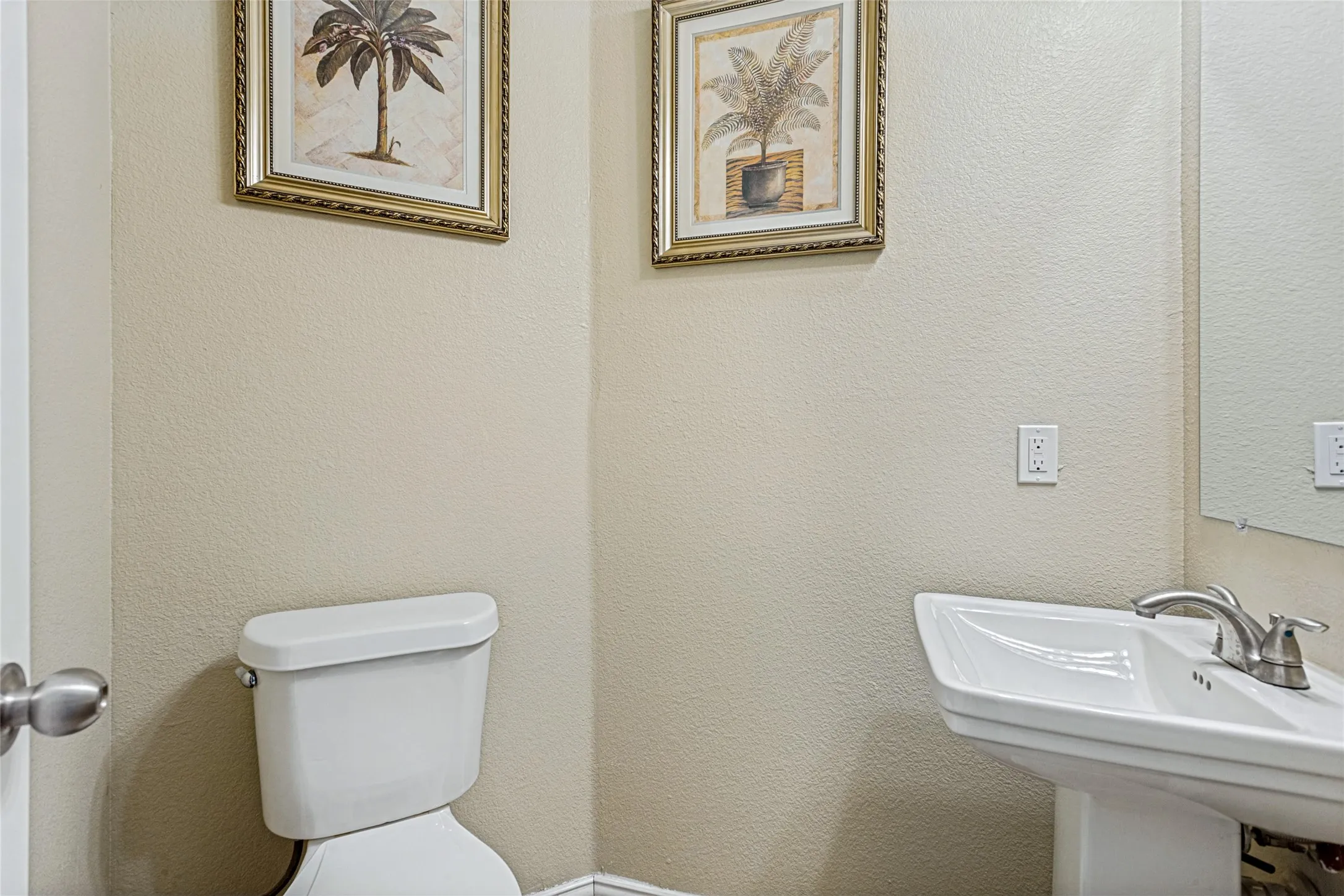 Pedestal sink with chrome-finish faucet, traditional toilet, and neutral wall tones