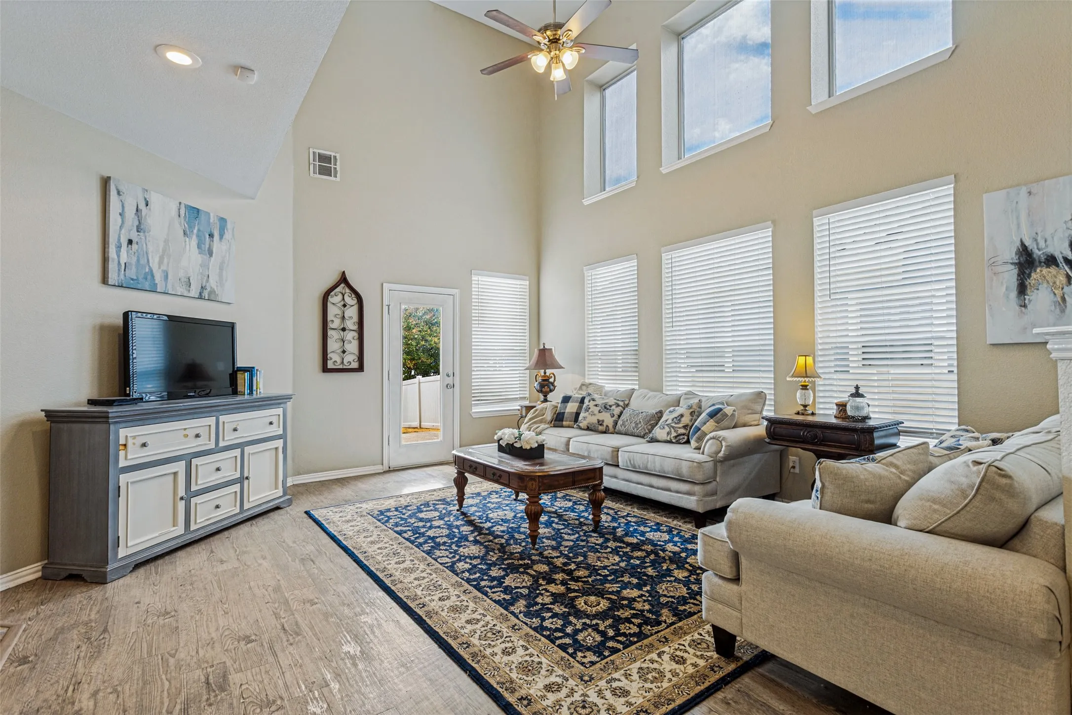 Vaulted ceilings with recessed lighting, wood-finish flooring, multiple windows with blinds, and a ceiling fan