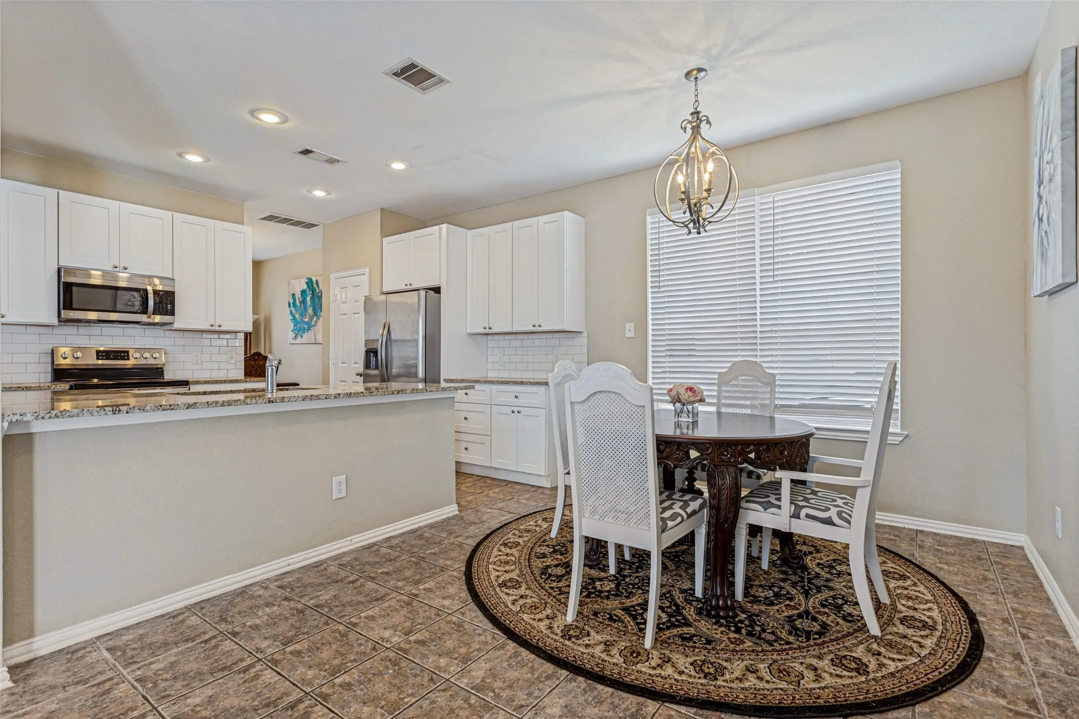 Kitchen featuring white cabinetry, stainless steel appliances, subway tile backsplash, and a breakfast bar