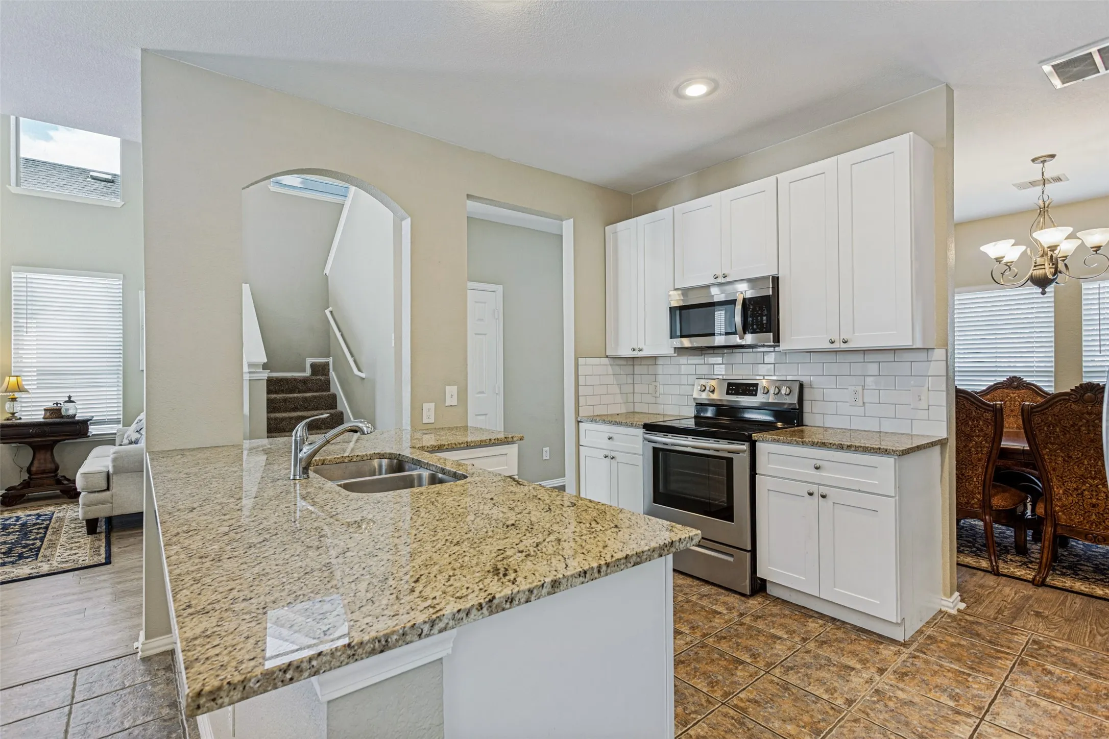 Kitchen featuring stainless steel appliances, white cabinetry, subway tile backsplash, and stone countertops