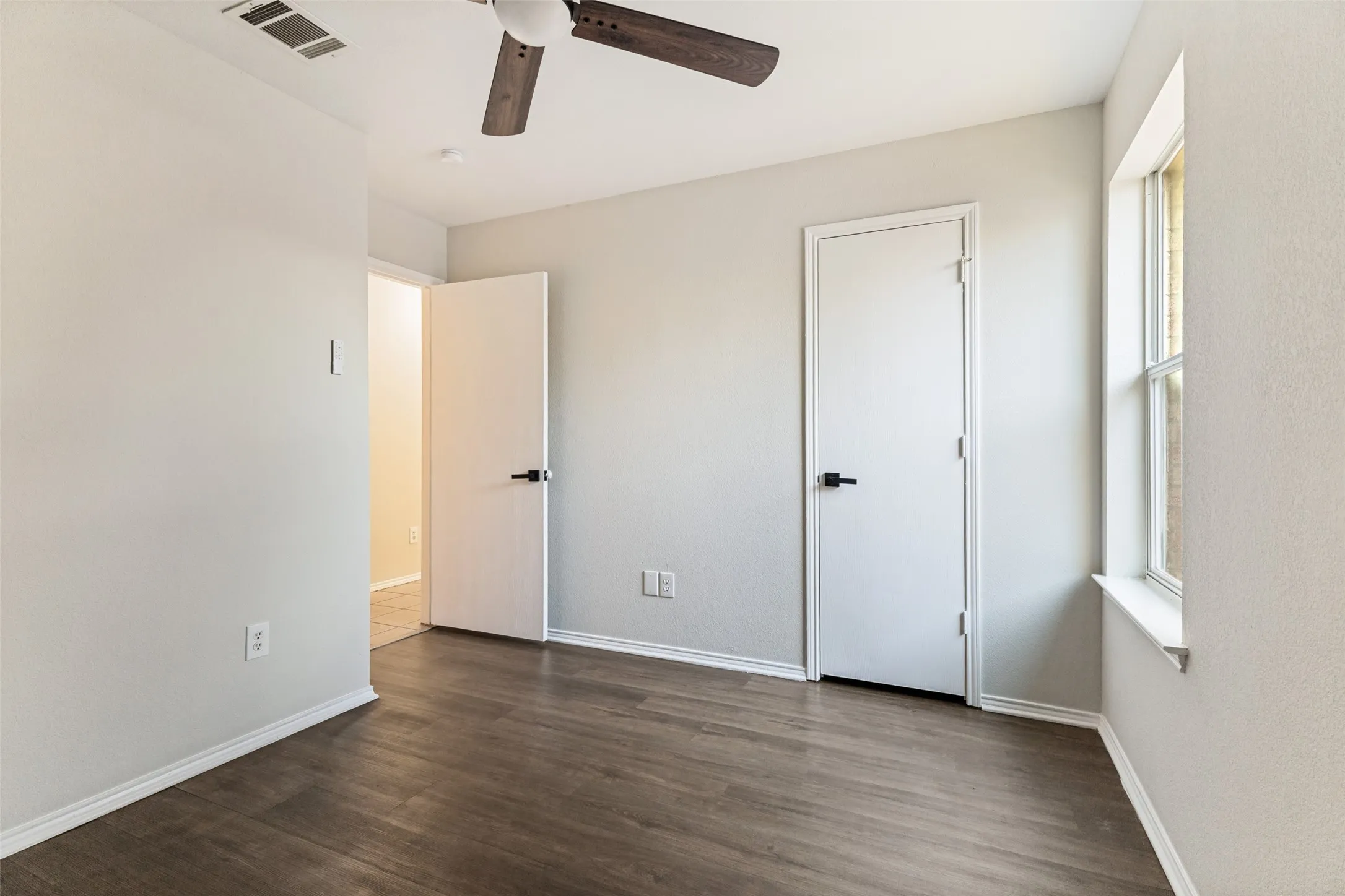 Wood-finish flooring, white walls, and a ceiling fan with wood-finish blades
