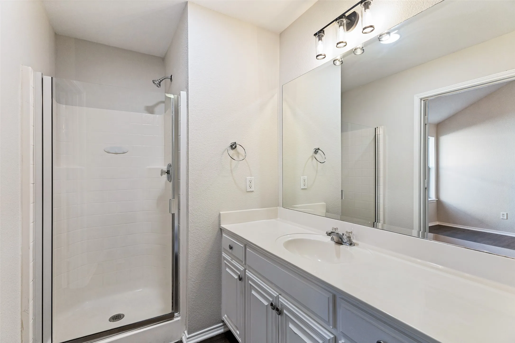White vanity with integrated sink, chrome faucet, and overhead bar lighting