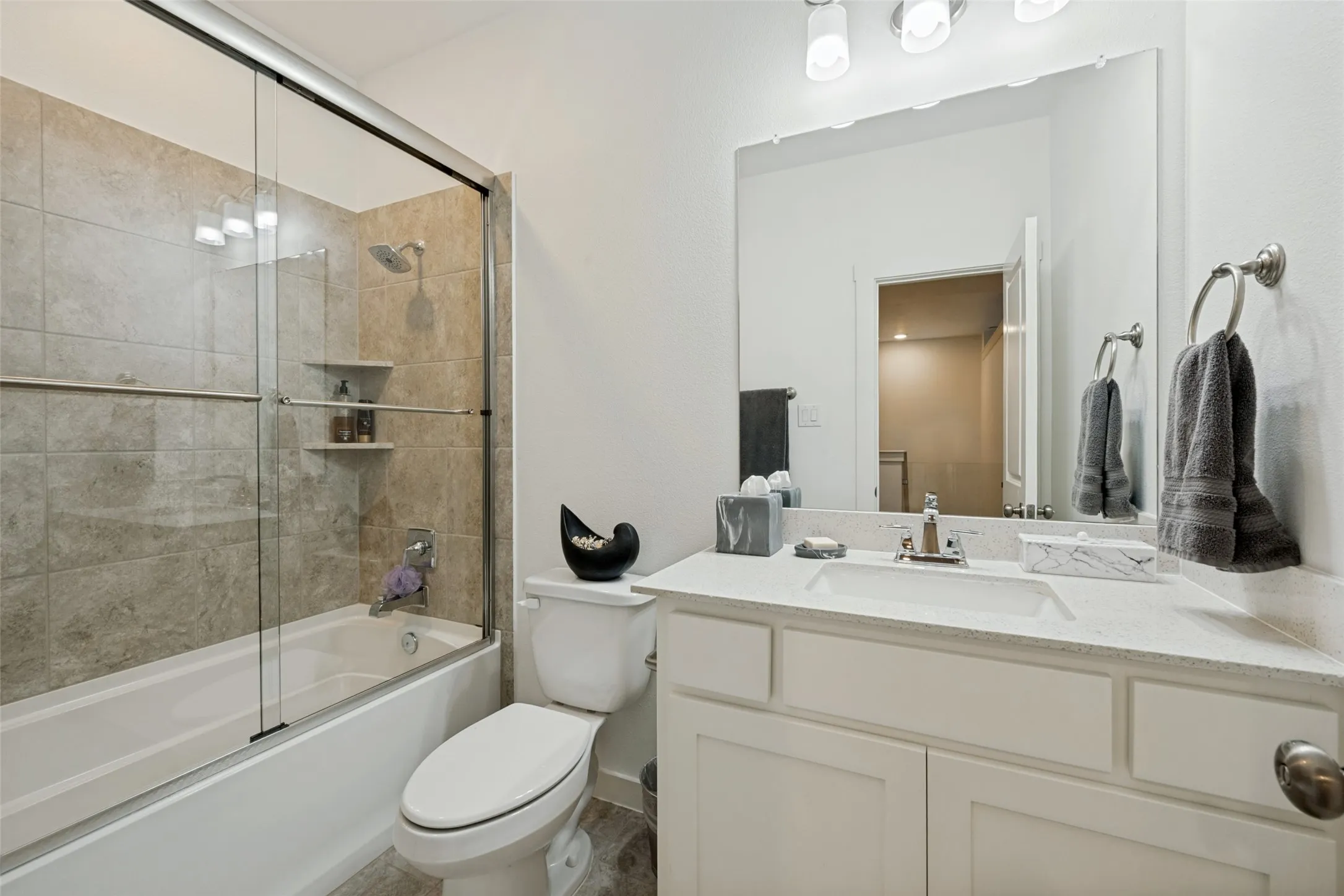 Built-in bathtub with glass sliding doors, tiled surround, and integrated shower head