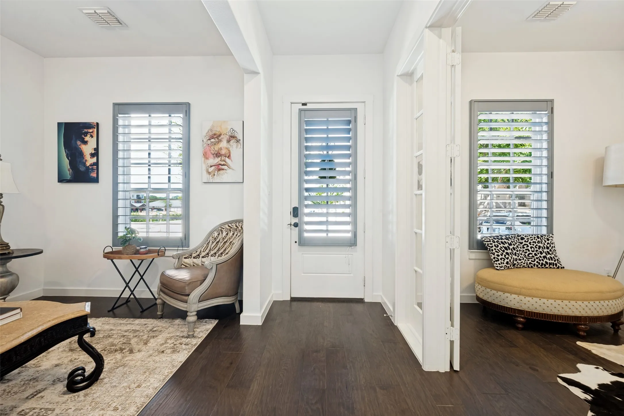 Dark wood-finish flooring throughout, white walls, and multiple windows with plantation shutters