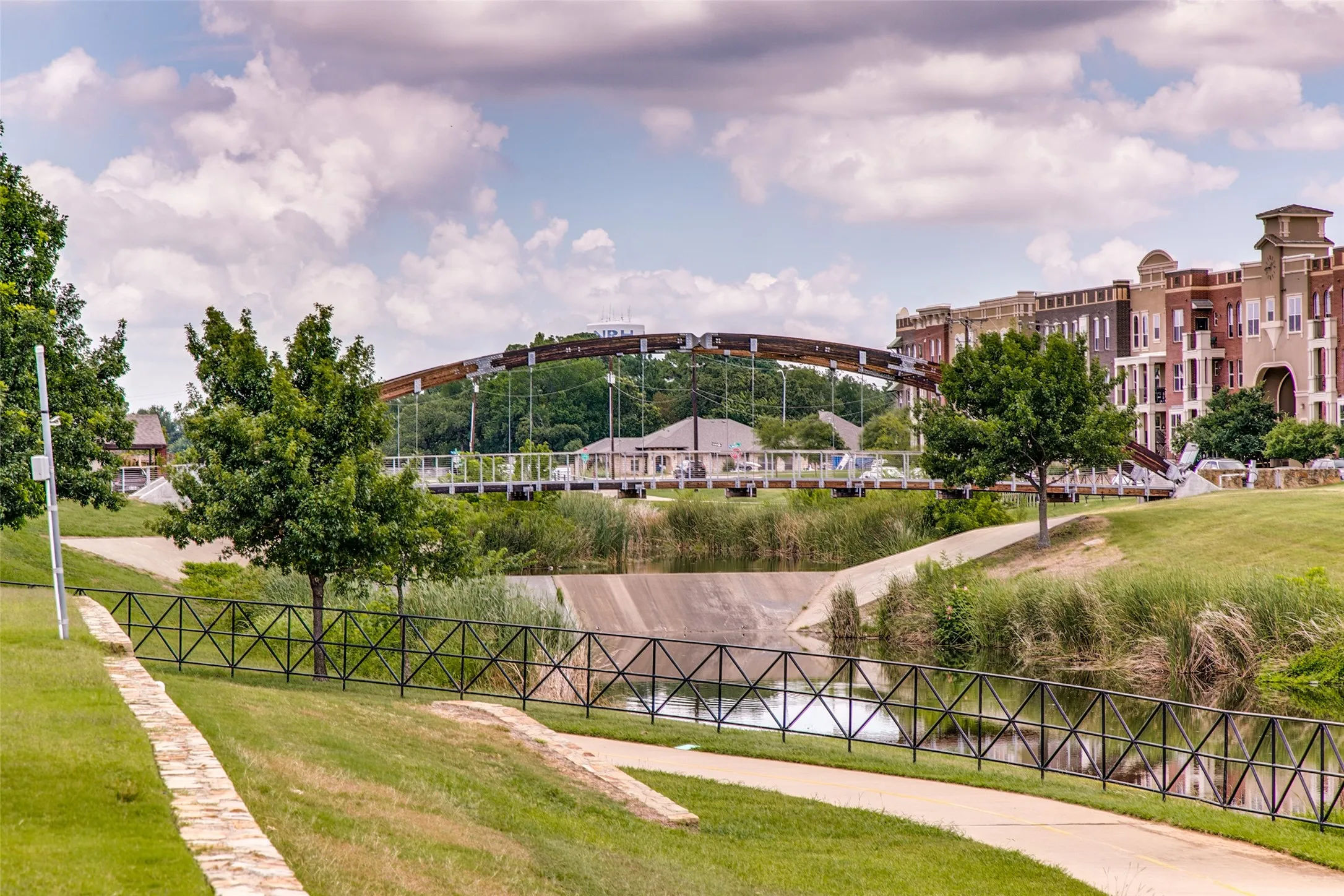 Landscaped green space featuring a decorative metal fence and a paved pathway