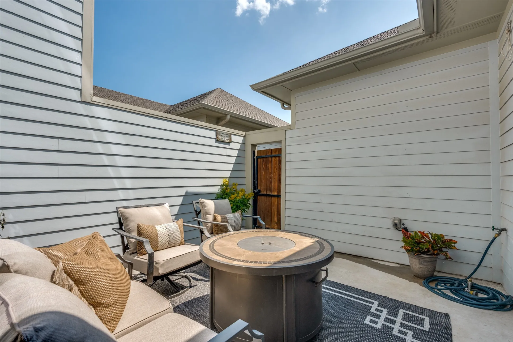 Private outdoor patio featuring a fire pit, concrete flooring, and horizontal siding