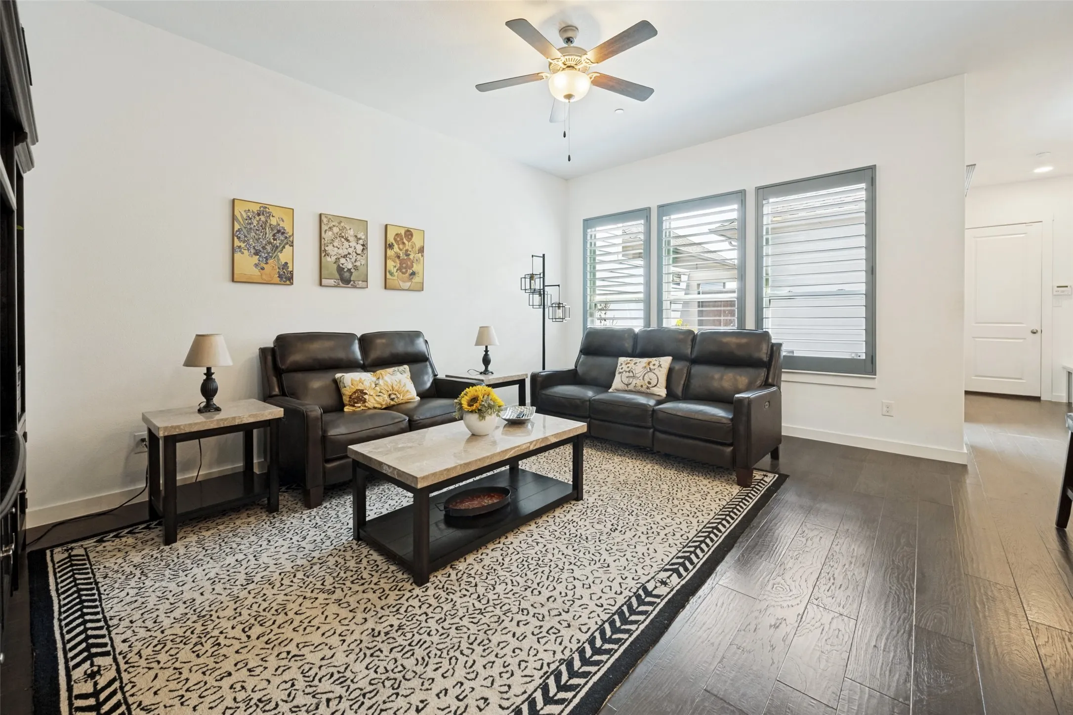 Recessed lighting, wood-finish flooring, ceiling fan with integrated lighting, and three windows with louvered shutters