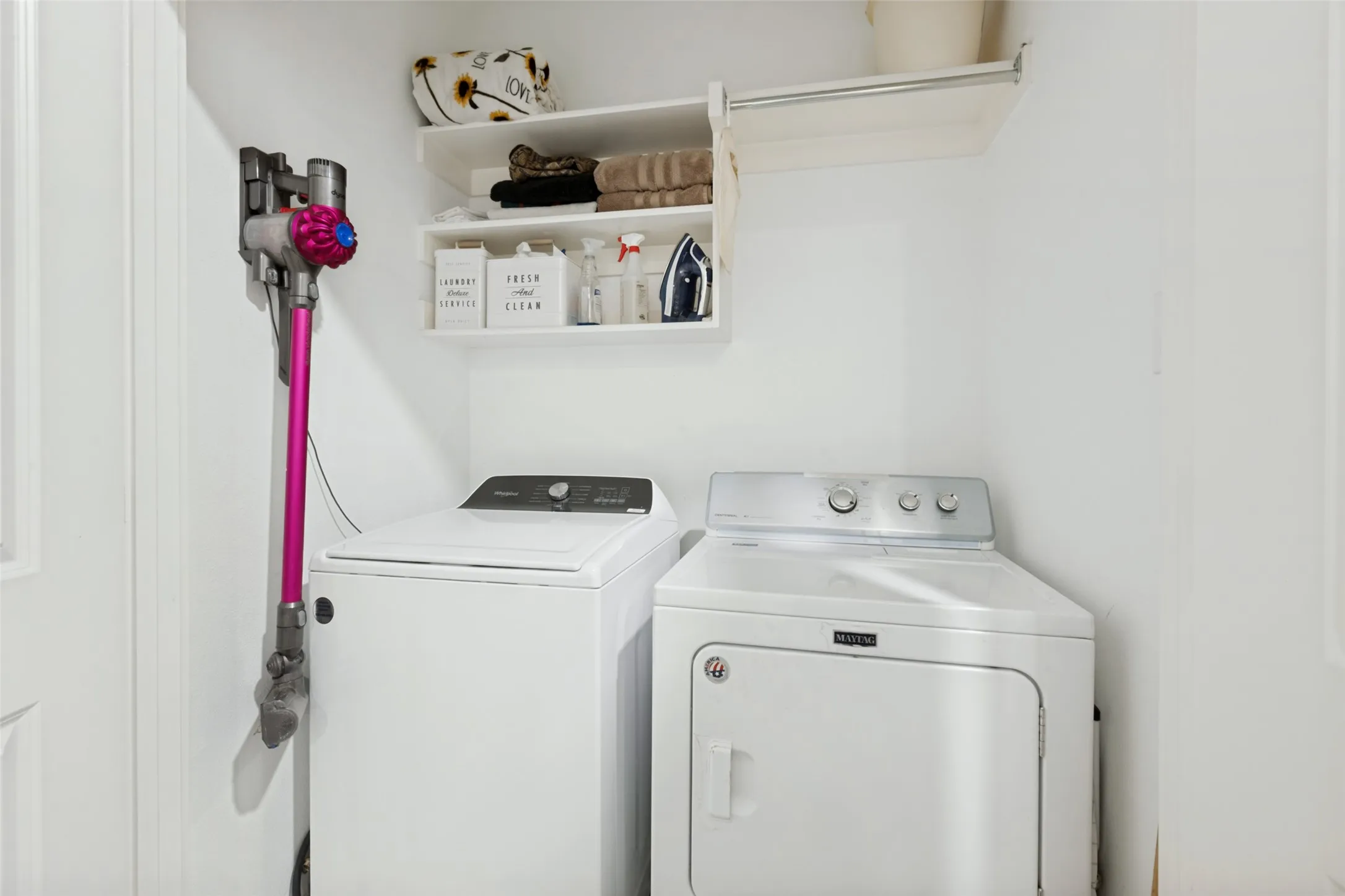White laundry area featuring an upper shelf and a clothing rod