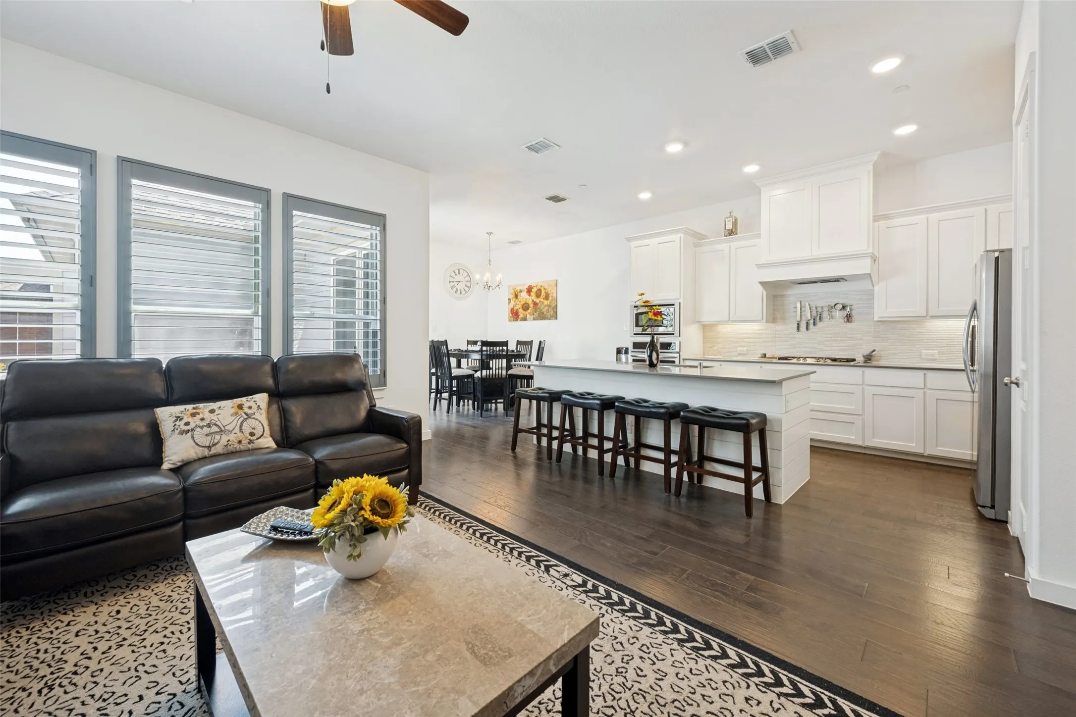 Open-concept living space with dark wood-finish flooring, white cabinetry, and recessed lighting