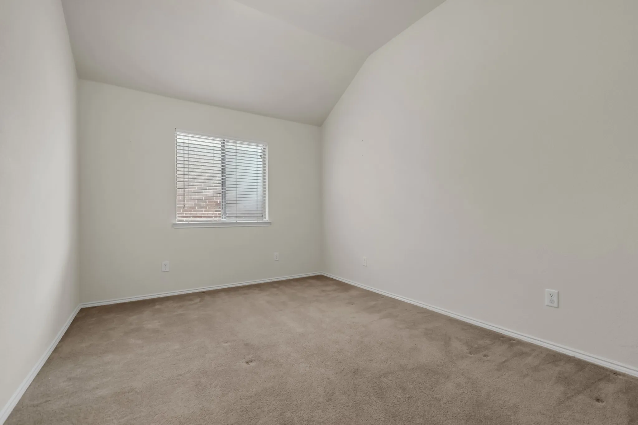 Neutral wall color, window with horizontal blinds, sloped ceiling, and carpet flooring