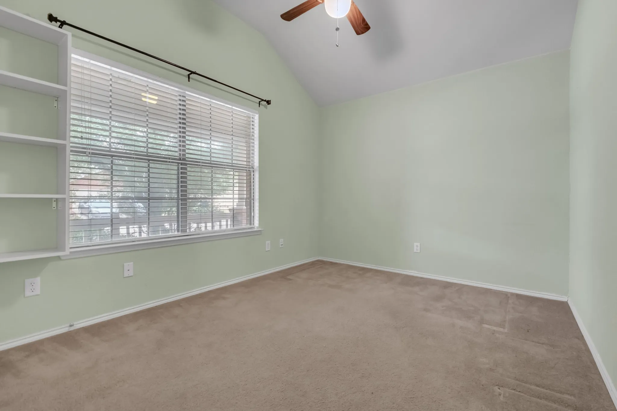 Vaulted ceiling, built-in shelving, window with blinds, ceiling fan with light, and carpet flooring